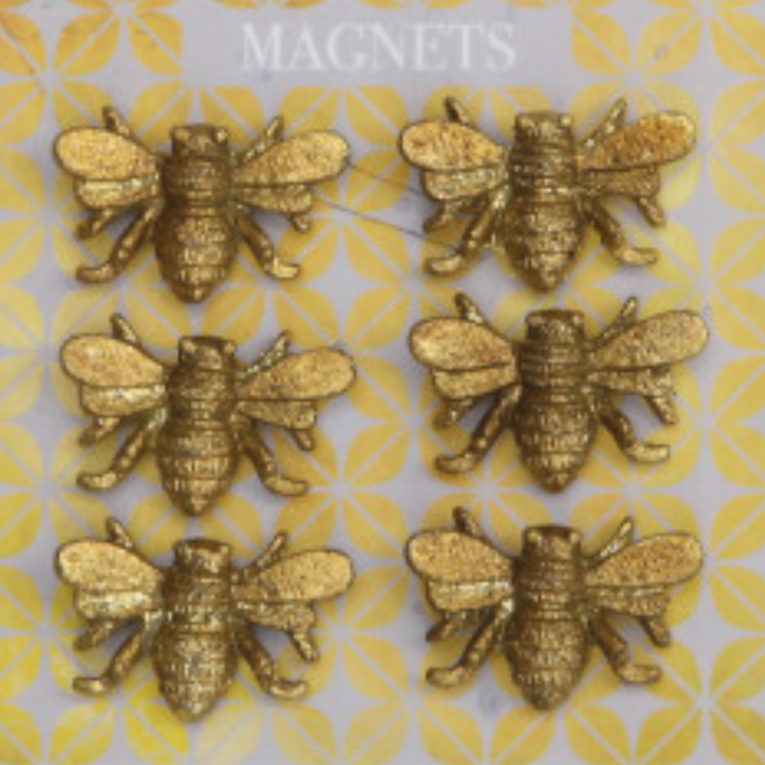 A set of six gold-finished pewter magnets shaped like bees, displayed on a patterned background.